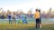 A group of children playing the Rockin’ Pockets bean bag toss game outdoors on a grassy field at sunset A group of children playing the Rockin’ Pockets bean bag toss game outdoors on a grassy field at sunset