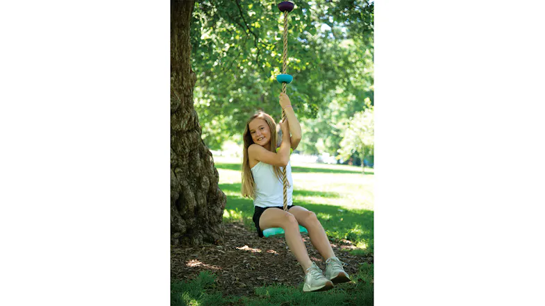 Child swinging on a rope with disc grips in a sunny green park Child swinging on a rope with disc grips in a sunny green park