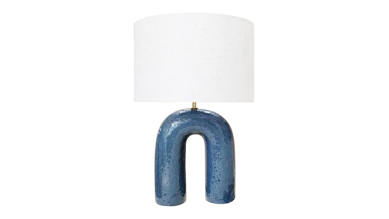 Modern ceramic table lamp with a unique U-shaped arch base in a deep blue glaze, topped with a white drum fabric shade Modern ceramic table lamp with a unique U-shaped arch base in a deep blue glaze, topped with a white drum fabric shade