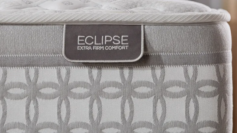 Eclipse mattress close up of top quilted comfort layer, border pattern, and end of bed label reading Eclipse Extra Firm Comfort. Eclipse mattress close up of top quilted comfort layer, border pattern, and end of bed label reading Eclipse Extra Firm Comfort.