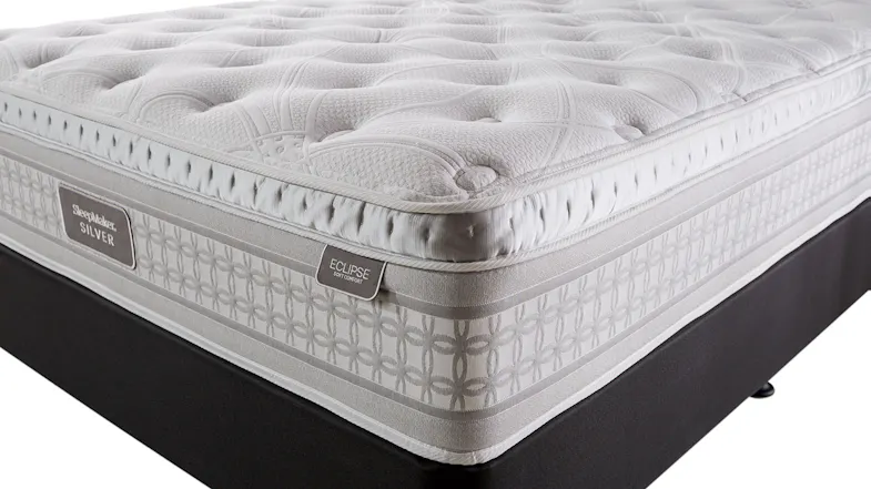 Eclipse mattress showing close up of top quilted comfort layer, border pattern, and two end of bed labels reading Sleepmaker Silver and Eclipse Soft Comfort. Eclipse mattress showing close up of top quilted comfort layer, border pattern, and two end of bed labels reading Sleepmaker Silver and Eclipse Soft Comfort.