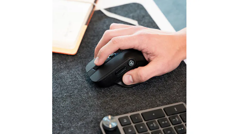 Hand using a mouse on a felt pad with keyboard and notebook in workspace Hand using a mouse on a felt pad with keyboard and notebook in workspace