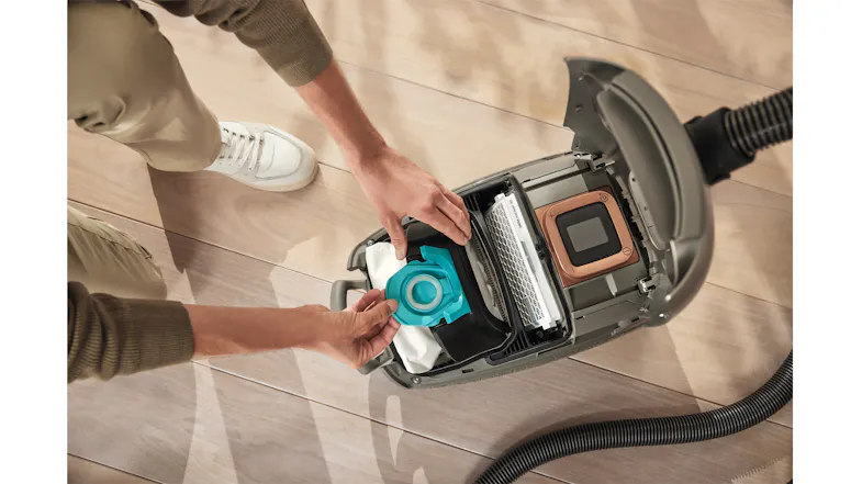 A person installing a vacuum bag into a canister vacuum A person installing a vacuum bag into a canister vacuum