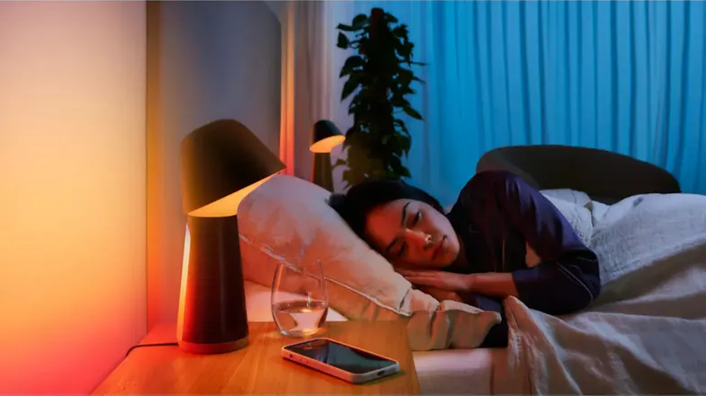 A person sleeping beside a glowing lamp and smartphone A person sleeping beside a glowing lamp and smartphone