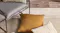 Close-up of Ecru Chevalier rug with mustard and textured white cushions near a chair Close-up of Ecru Chevalier rug with mustard and textured white cushions near a chair