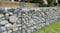 Gabion wall made of galvanised wire mesh filled with large smooth stones in a landscaped garden Gabion wall made of galvanised wire mesh filled with large smooth stones in a landscaped garden