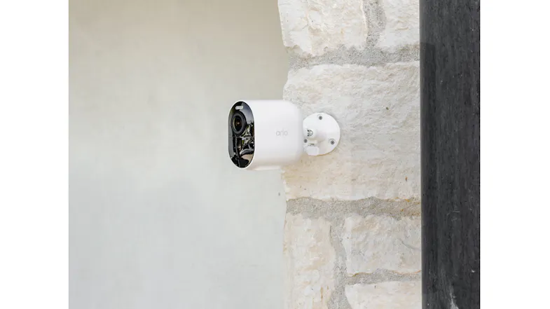 White security camera mounted to a light-colored textured stone wall White security camera mounted to a light-colored textured stone wall