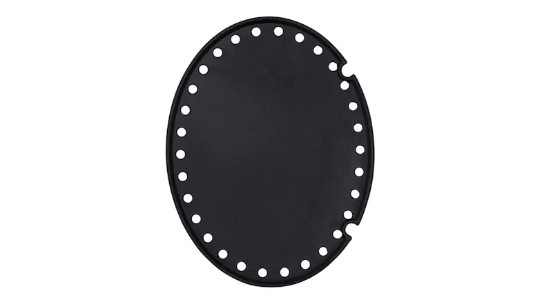 A black, oval-shaped cast iron hotplate with small holes around the edge A black, oval-shaped cast iron hotplate with small holes around the edge