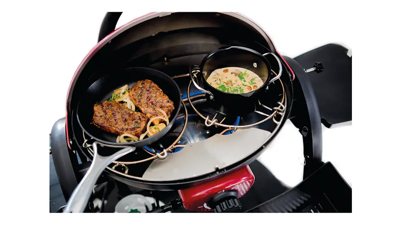Food cooking on a round grill, utilising a Ziggy Trivet to support a skillet and small pot Food cooking on a round grill, utilising a Ziggy Trivet to support a skillet and small pot