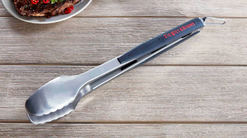 A pair of stainless steel 16-inches BBQ tongs with handles bearing the 'Ziegler & Brown' logo, resting on a rustic wooden table A pair of stainless steel 16-inches BBQ tongs with handles bearing the 'Ziegler & Brown' logo, resting on a rustic wooden table