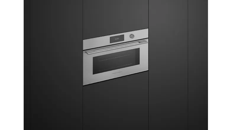 Angled view of the closed microwave oven integrated into black cabinetry, highlighting sleek silver finish Angled view of the closed microwave oven integrated into black cabinetry, highlighting sleek silver finish
