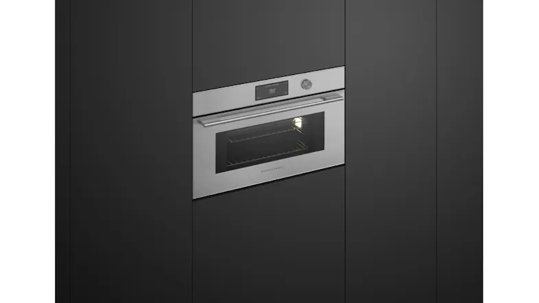 Angled view of the microwave oven with interior light on, revealing cooking space and wire rack inside Angled view of the microwave oven with interior light on, revealing cooking space and wire rack inside