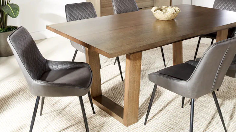 Close-up of the Whitehaven dining table with a Smoke Tassie Oak Veneer finish, surrounded by cushioned chairs Close-up of the Whitehaven dining table with a Smoke Tassie Oak Veneer finish, surrounded by cushioned chairs