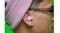 Close-up view of a person wearing a pink JLab earbud Close-up view of a person wearing a pink JLab earbud