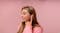 A person smiling and touching an earbud, matching a pink top A person smiling and touching an earbud, matching a pink top