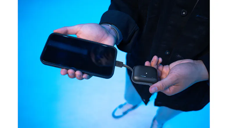 Person charging a phone using an earbud case Person charging a phone using an earbud case