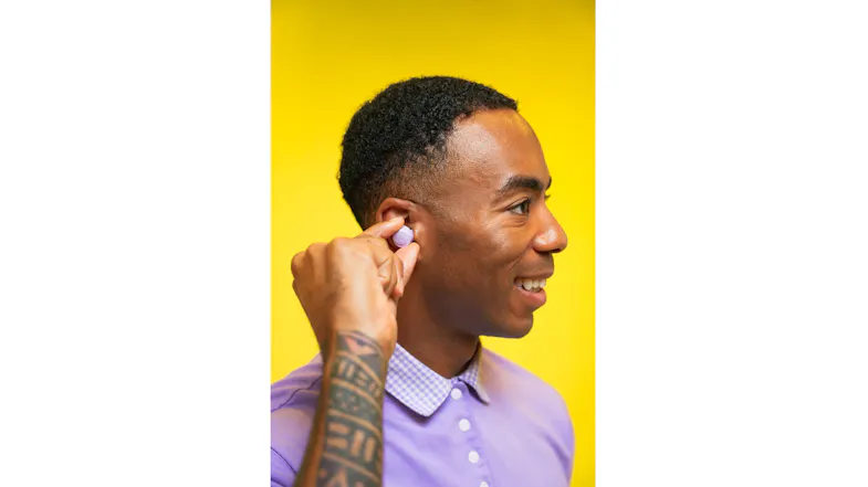 Person inserting wireless earbuds with a tattooed arm and a checkered collar shirt Person inserting wireless earbuds with a tattooed arm and a checkered collar shirt