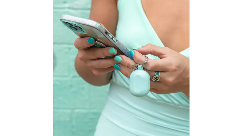 Person holding phone and mint keychain earbud case Person holding phone and mint keychain earbud case