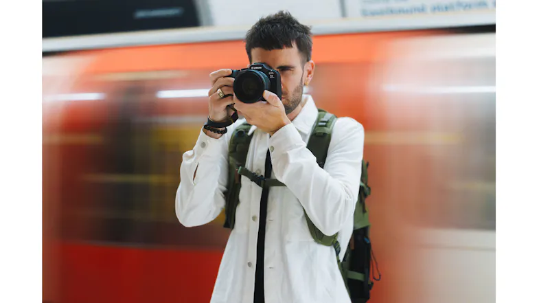 Photographer shooting with the EOS R6 Mark III as a train blurs by in the background Photographer shooting with the EOS R6 Mark III as a train blurs by in the background