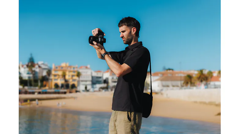 Photographer using the Canon Mirrorless Camera to take a picture of a coastal town and beach Photographer using the Canon Mirrorless Camera to take a picture of a coastal town and beach