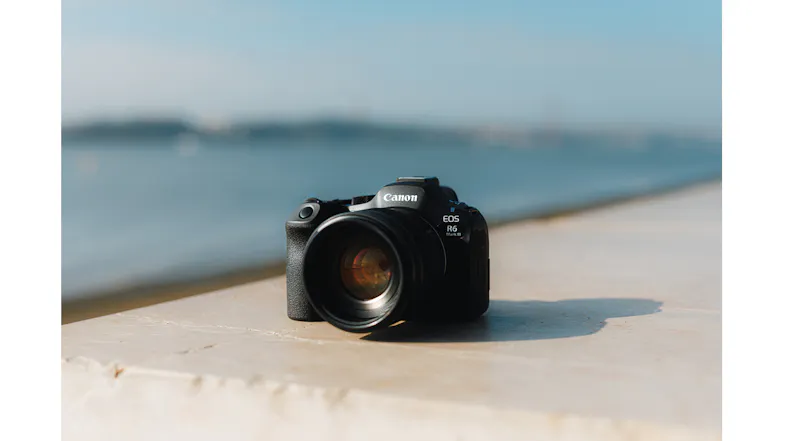 Canon EOS R6 Mark III camera, sitting on a stone wall near a body of water Canon EOS R6 Mark III camera, sitting on a stone wall near a body of water