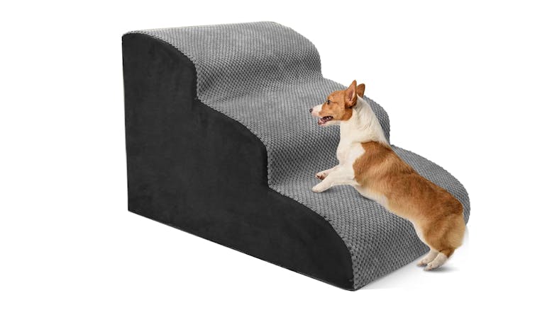 A right-angled view of a foam pet stairs with a dog climbing on it A right-angled view of a foam pet stairs with a dog climbing on it