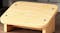 Ergonomic wooden footrest with slanted surface and smooth edges positioned under a desk on hardwood flooring Ergonomic wooden footrest with slanted surface and smooth edges positioned under a desk on hardwood flooring