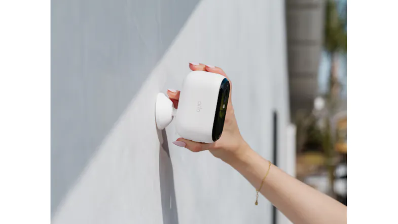 A person adjusting the Arlo camera on a wall A person adjusting the Arlo camera on a wall