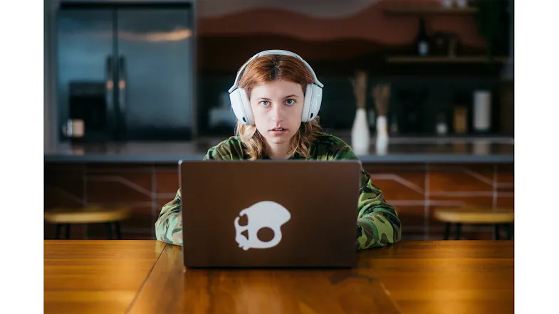Person in the kitchen with a laptop and white headphones Person in the kitchen with a laptop and white headphones