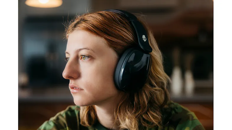 Close-up of a person in a camo shirt wearing Skullcandy headphones indoors Close-up of a person in a camo shirt wearing Skullcandy headphones indoors