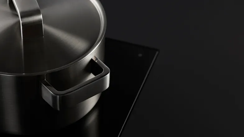 Brushed steel pot with lid on glossy black cooktop Brushed steel pot with lid on glossy black cooktop