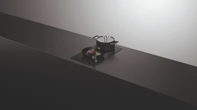 Black pan and pot on active cooktop with red touch controls Black pan and pot on active cooktop with red touch controls