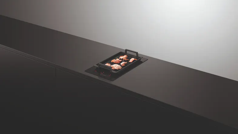 Induction cooktop with griller and meat on top Induction cooktop with griller and meat on top