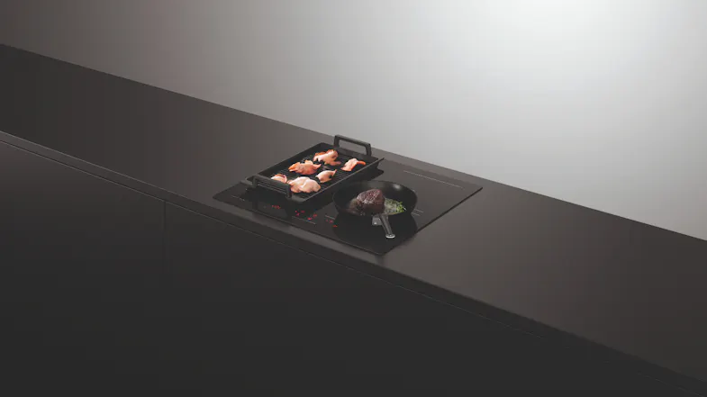 Black pan and pot on active cooktop with red touch controls Black pan and pot on active cooktop with red touch controls