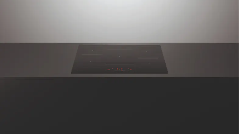 Wide front view of a black induction cooktop installed in a sleek dark countertop, showing its minimalist design Wide front view of a black induction cooktop installed in a sleek dark countertop, showing its minimalist design