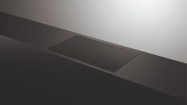 Angled view of an induction cooktop integrated into a modern kitchen counter Angled view of an induction cooktop integrated into a modern kitchen counter