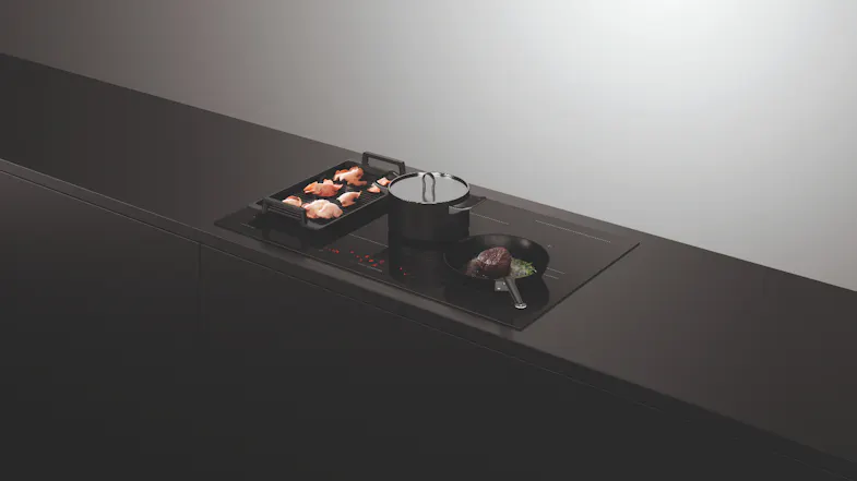 Cooktop in use with two pots and a frying pan, cooking steak and vegetables Cooktop in use with two pots and a frying pan, cooking steak and vegetables