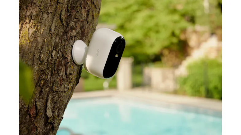 Arlo camera on a wooden post with a house and greenery Arlo camera on a wooden post with a house and greenery