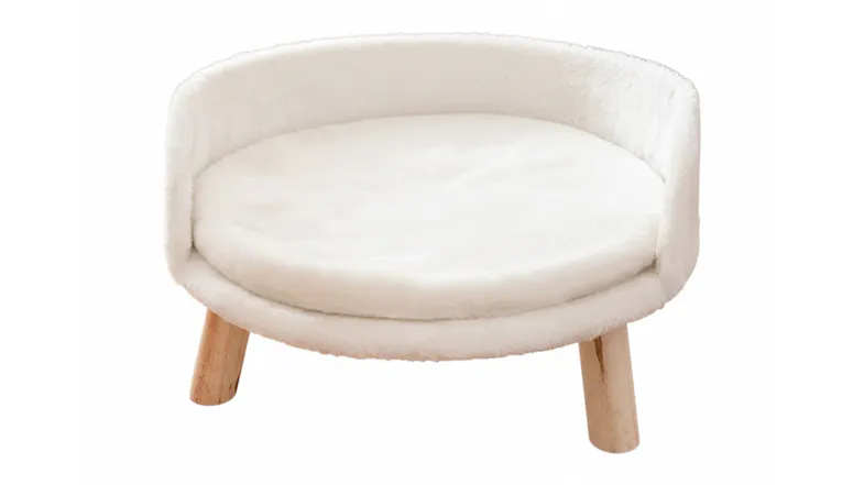 Close-up view of the round, fluffy white elevated pet bed with natural wood legs Close-up view of the round, fluffy white elevated pet bed with natural wood legs