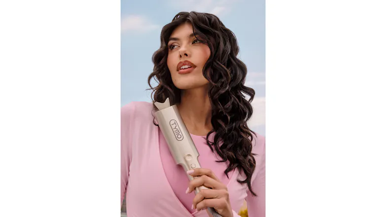 A person in a pink top holding a gold TYMO curler A person in a pink top holding a gold TYMO curler