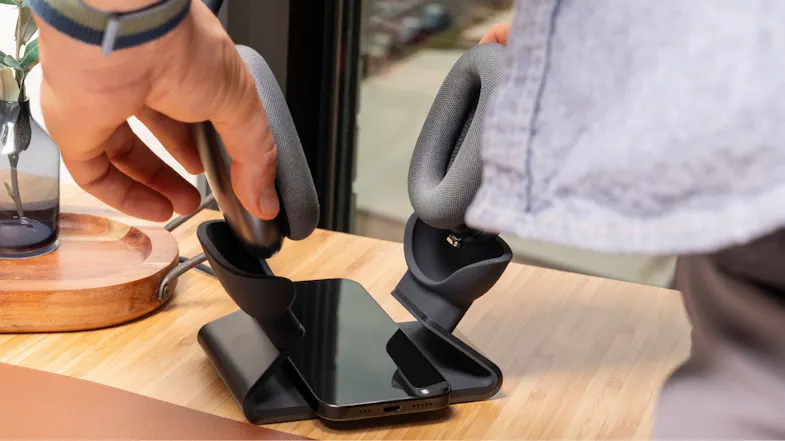 A person placing AirPods Max onto a wireless charging dock A person placing AirPods Max onto a wireless charging dock