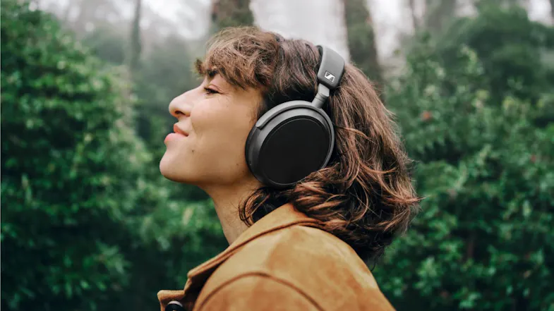Outdoor image of the headphones worn, showing lush green foliage in the background Outdoor image of the headphones worn, showing lush green foliage in the background