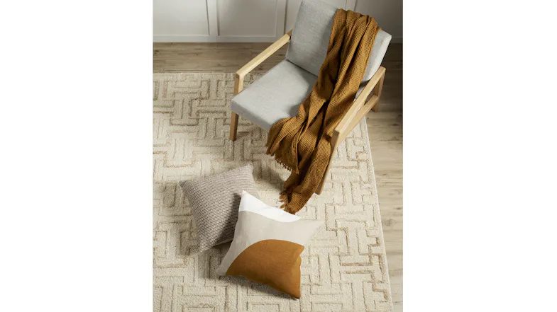 Ecru geometric rug on a wood floor with a light wood chair, pillows, and a mustard throw Ecru geometric rug on a wood floor with a light wood chair, pillows, and a mustard throw