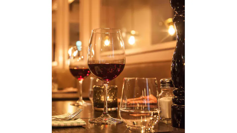 Red wine in a stem glass on a dim, warm restaurant table Red wine in a stem glass on a dim, warm restaurant table