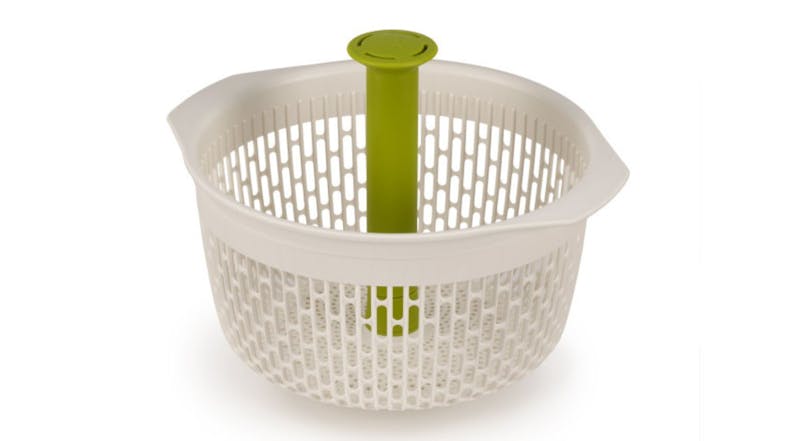 White colander with green pump spindle in the centre, designed for rinsing and spinning salad greens White colander with green pump spindle in the centre, designed for rinsing and spinning salad greens