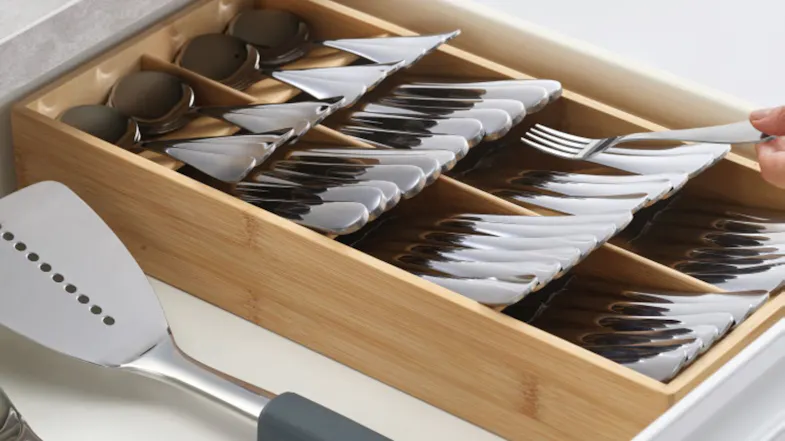 Bamboo cutlery organiser in a drawer holding spoons and forks, with utensils placed beside it Bamboo cutlery organiser in a drawer holding spoons and forks, with utensils placed beside it