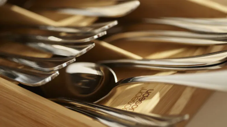 Close-up of Joseph Joseph bamboo cutlery organiser holding neatly arranged stainless steel forks and spoons Close-up of Joseph Joseph bamboo cutlery organiser holding neatly arranged stainless steel forks and spoons