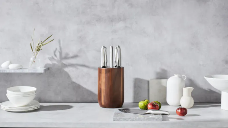 A modern kitchen counter with a wooden knife block, white dishes, vases, and fresh tomatoes A modern kitchen counter with a wooden knife block, white dishes, vases, and fresh tomatoes