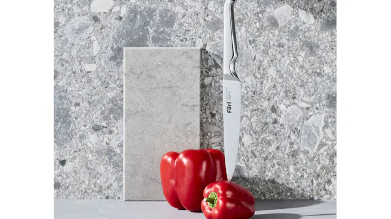 A front angle of a sleek stainless-steel knife standing upright beside two red bell peppers A front angle of a sleek stainless-steel knife standing upright beside two red bell peppers