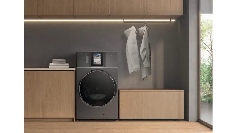 Washer dryer installed in a modern laundry space with wooden cabinetry and hanging coats beside it Washer dryer installed in a modern laundry space with wooden cabinetry and hanging coats beside it